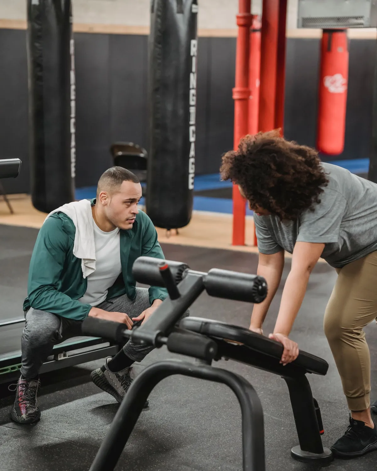 Personal Trainer unterstützt eine Kundin beim begleiteten Training im Fitnessstudio