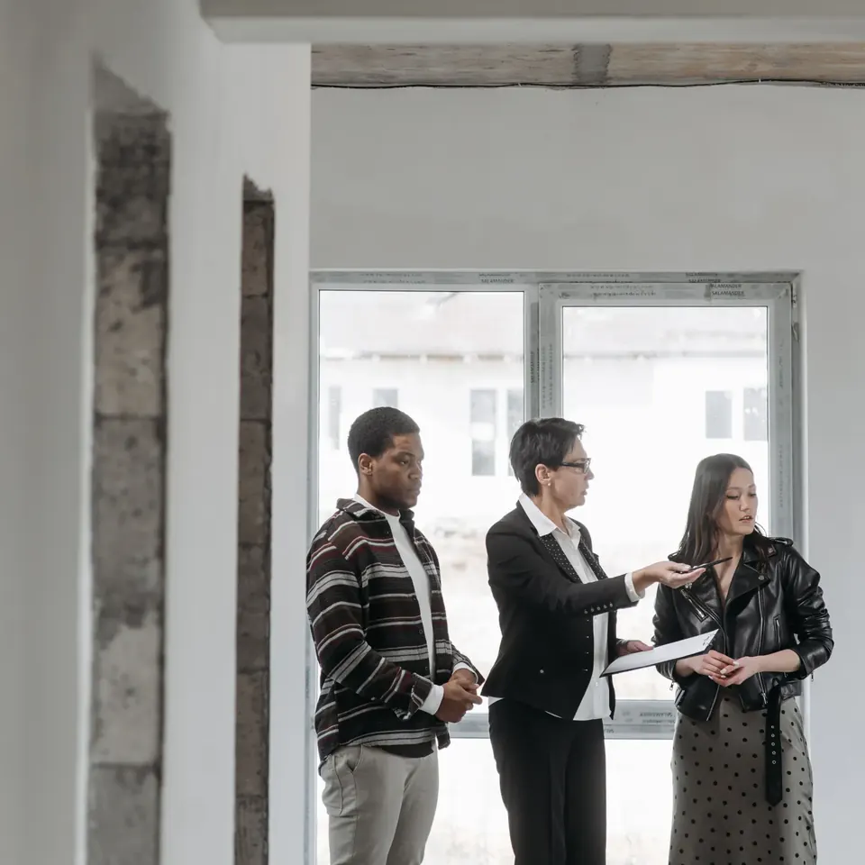 Immobilienmaklerin zeigt einem Paar bei der Besichtigung eine Wohnung